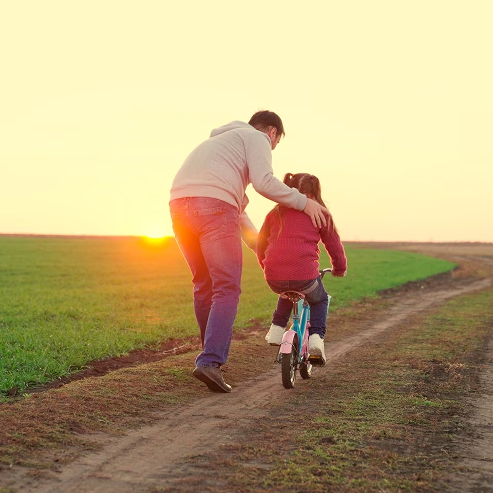 A father helping his child learn to ride a bike