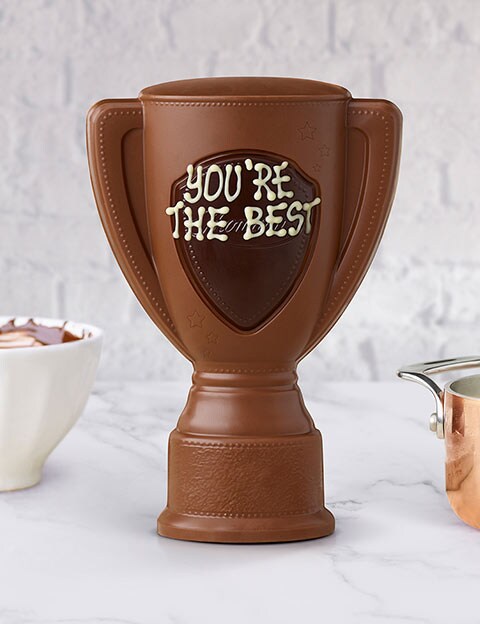 Thorntons milk chocolate trophy hand iced with &amp;amp;apos;you&amp;amp;apos;re the best&amp;amp;apos; on a marble table with a copper pan
