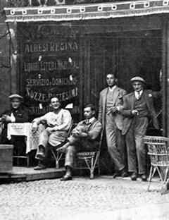 Men standing outside of a shop.