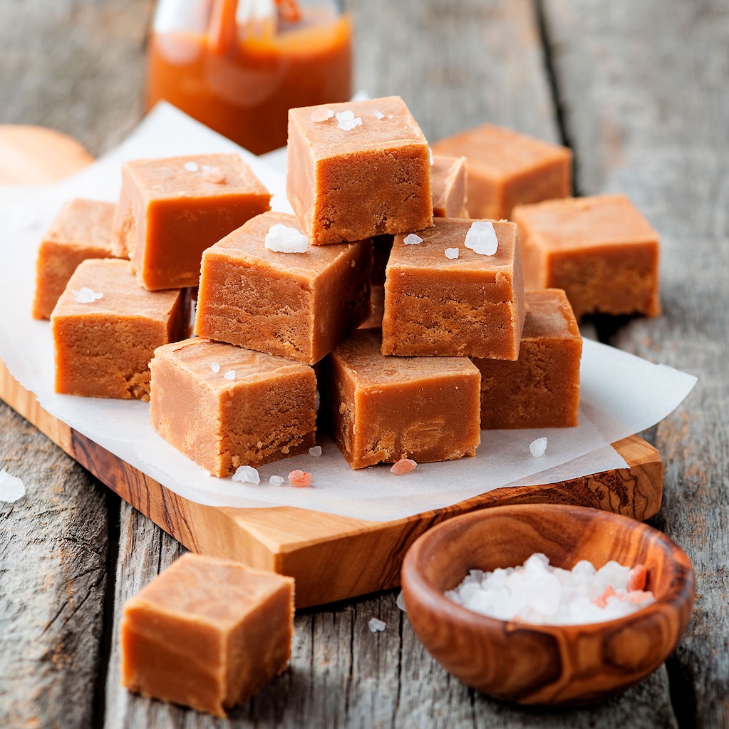 Cubes of Creamy Fudge stacked on a wooden board.