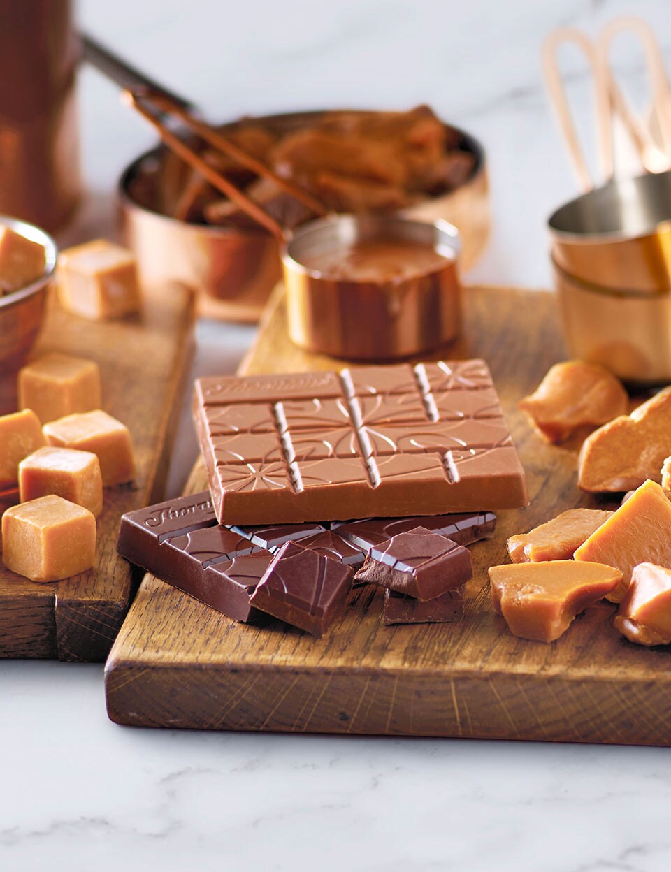 An assortment of chocolate and toffee on wooden chopping boards.