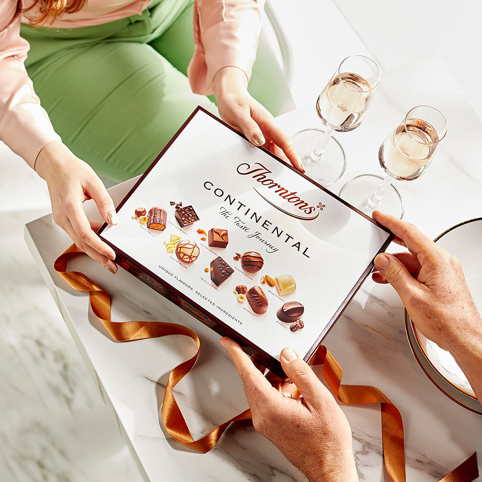 Someone giving a box of Continental Collection chocolates as a gift.