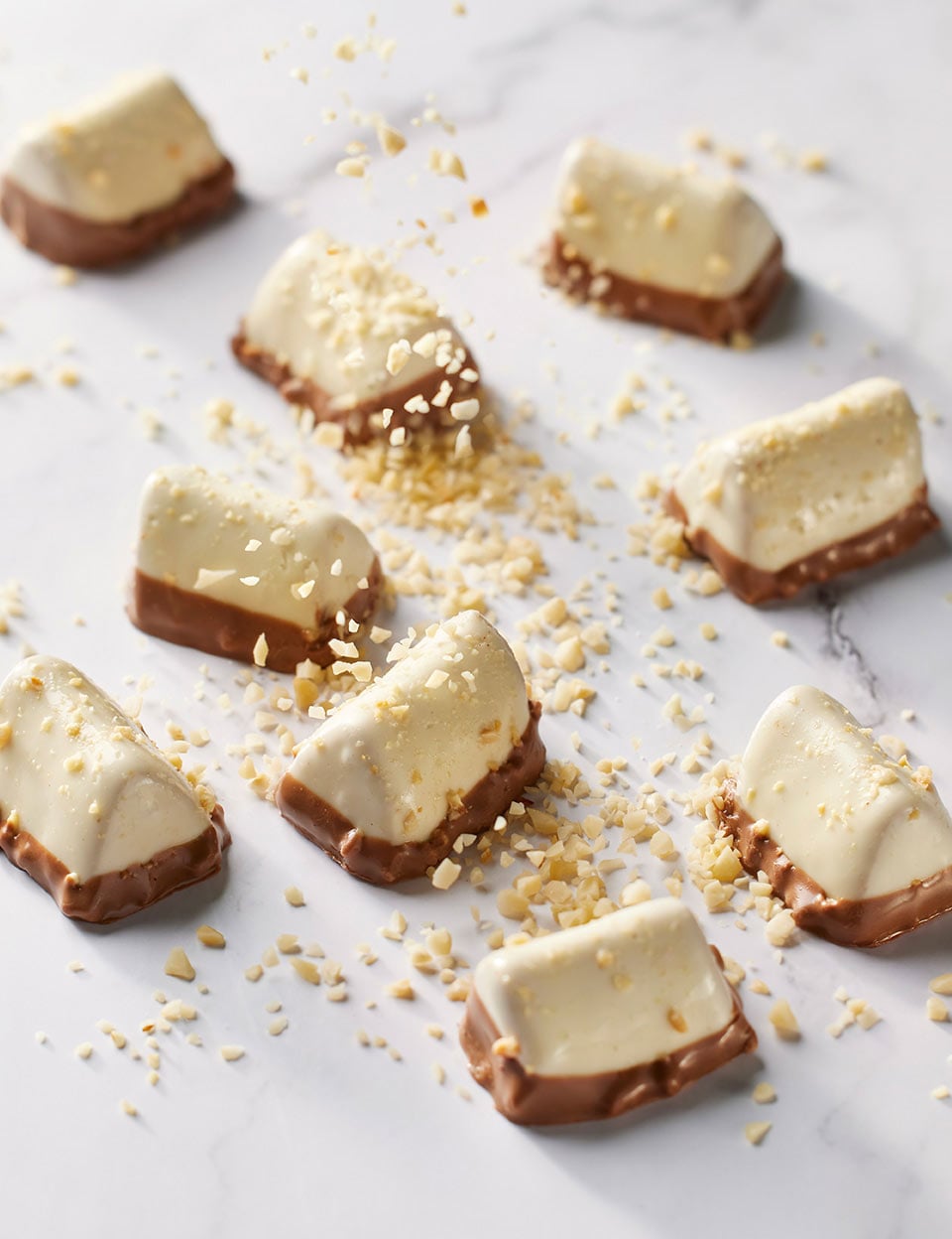 Thorntons Classic Crunchy Praline chocolate ona marble table being sprinkled with roasted almonds