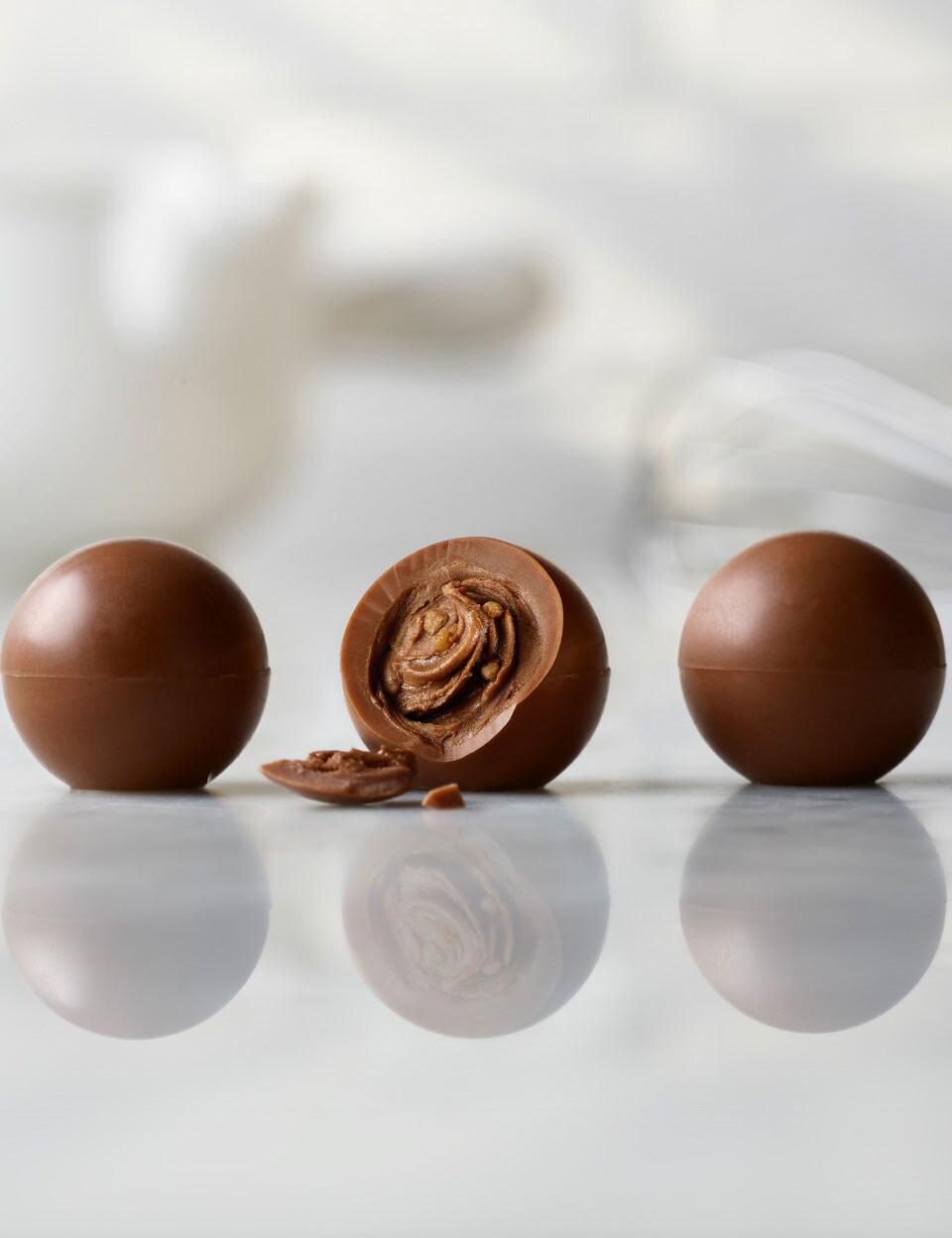 Three Thorntons Pearls chocolates in a line on a marble surface.