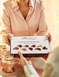 Person giving a box of Thorntons Continental as a gift to another.